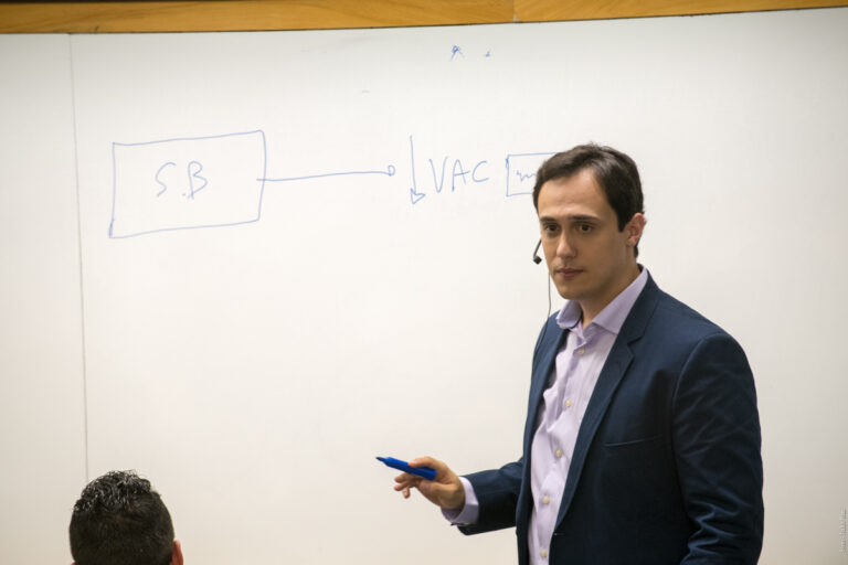 Lucas Naves dando aula, escrevendo no quadro branco